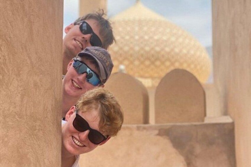 Two people peeking over a wall with a dome-shaped structure in the background. 4