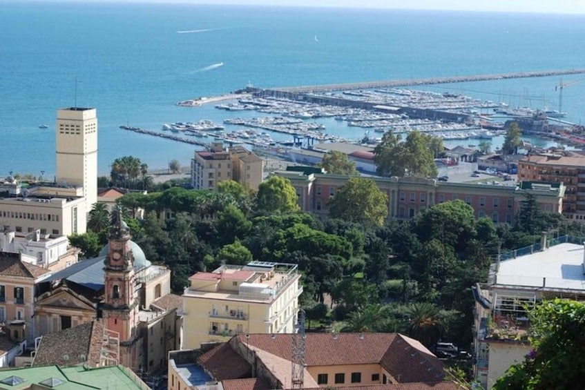 A coastal cityscape with a marina filled with boats, historic buildings, and a prominent tower. 2