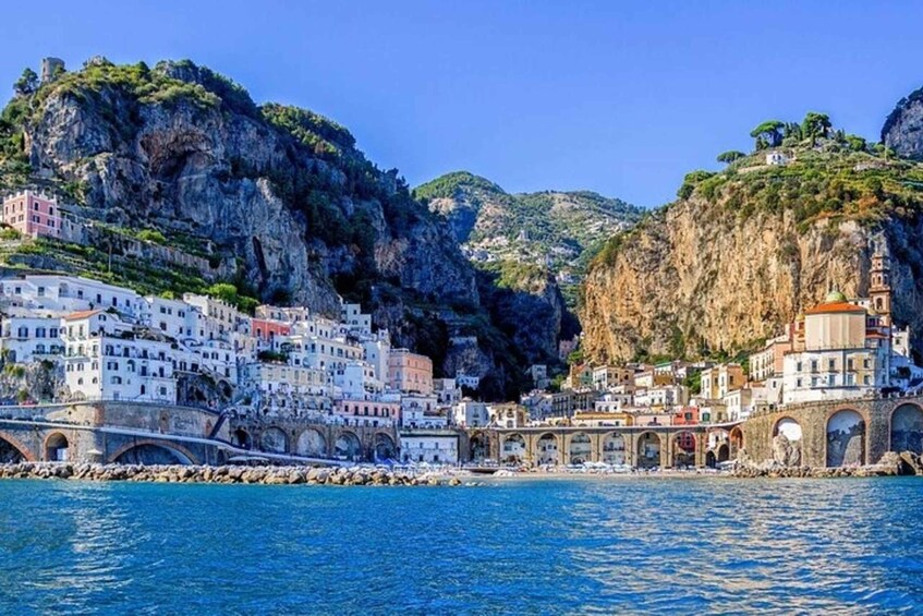 A coastal town with white buildings, a bridge, and a rocky cliff. 3