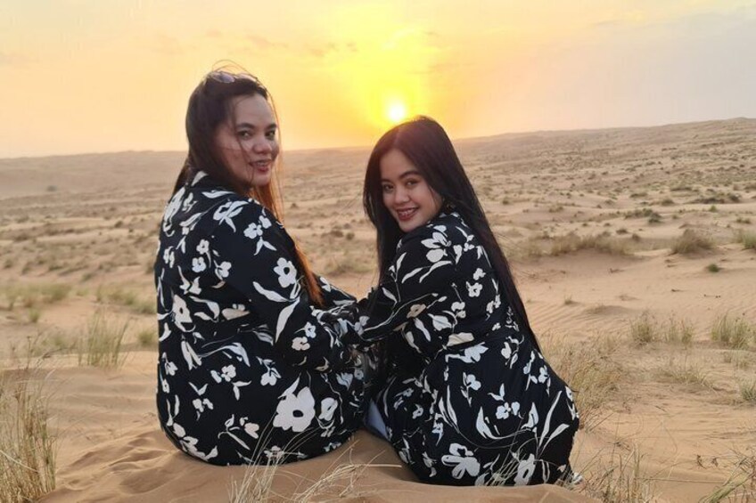 Two people sitting on sand dunes during sunset. 2