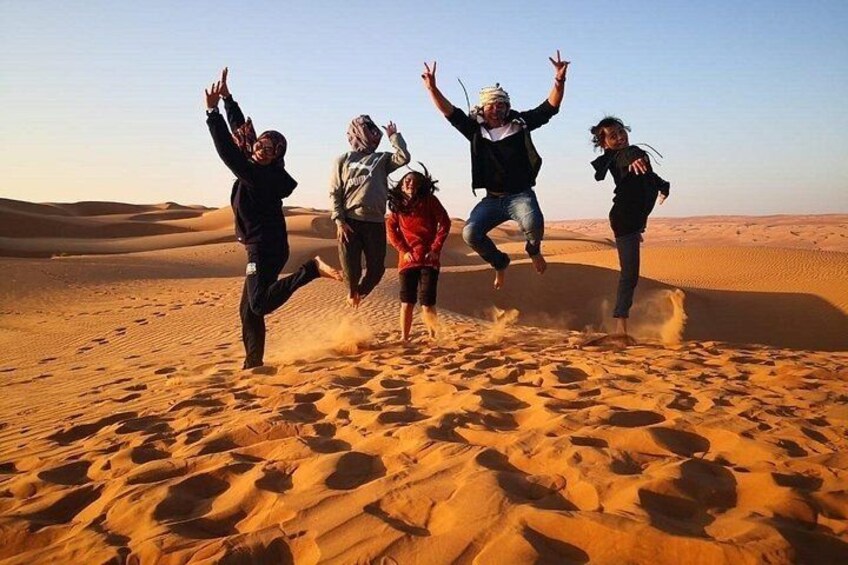 People jumping in a desert with sand dunes in the background. 5