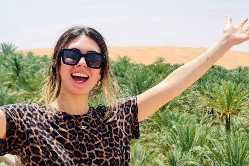 A person in a leopard print top with palm trees and a desert in the background. 4