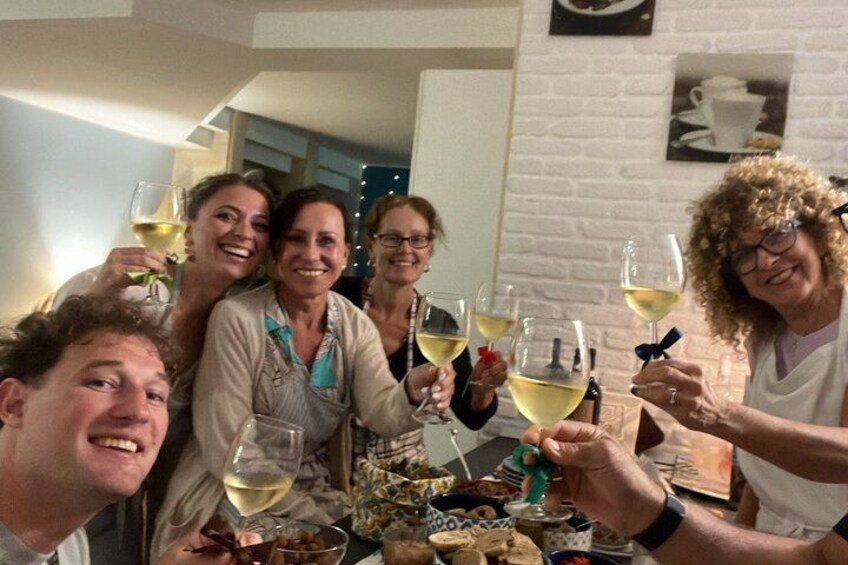 A group of people toasting with wine glasses at a table with food. 4