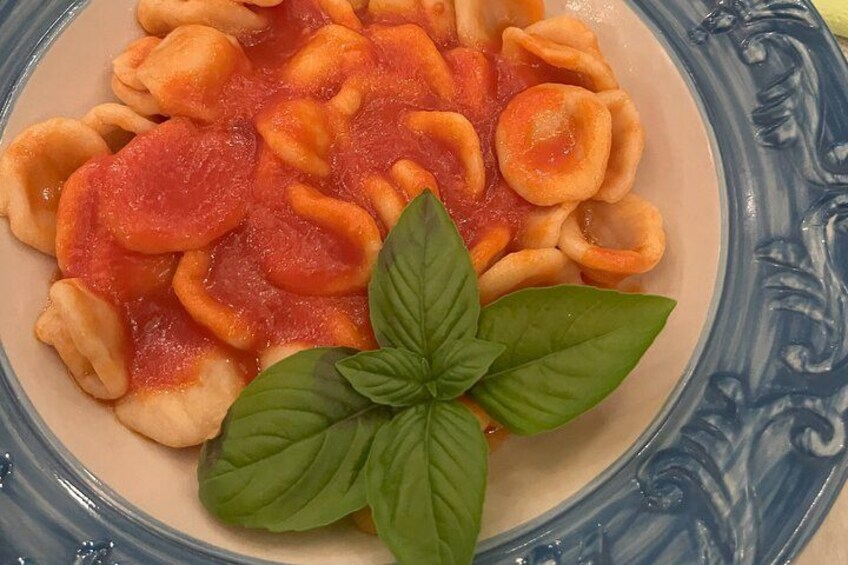 A plate of ravioli with tomato sauce and basil leaves. 2