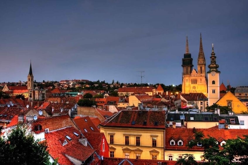 A cityscape with a prominent church with two spires and a clock tower, surrounded by red-roofed buildings. 4