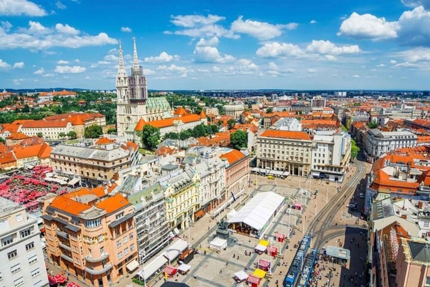 A cityscape with a prominent cathedral, red-roofed buildings, and a busy square with market stalls. 5