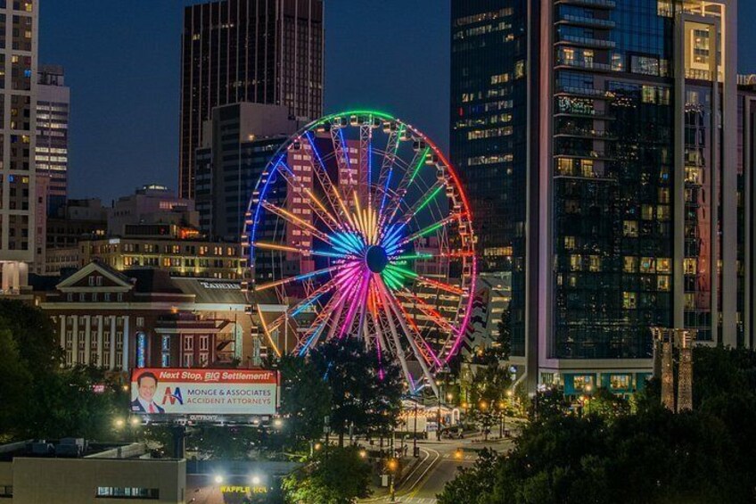 A brightly lit Ferris wheel with colorful lights against a city skyline at night. 5