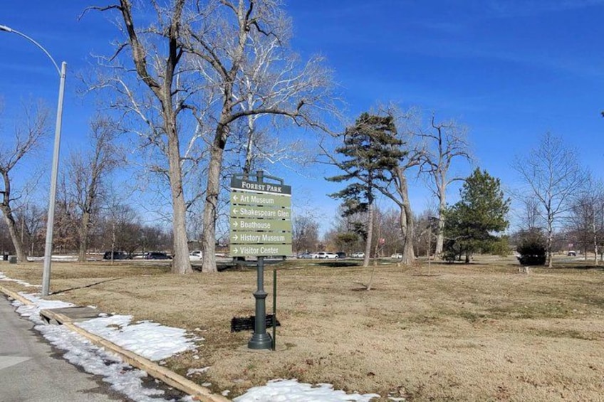 A signpost in a park with directions to various attractions including an art museum, Shakespeare Garden, and a history museum. 4