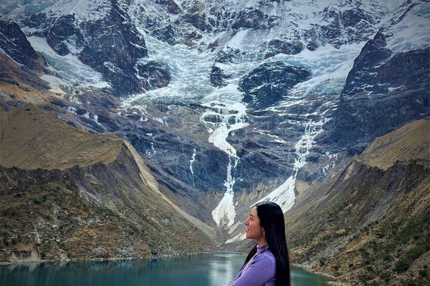 A person standing by a lake with a glacier in the background. 1