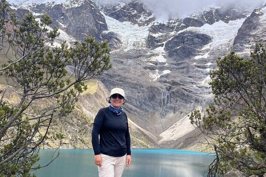 A person standing by a calm lake with mountains in the background. 5