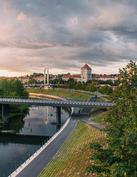 A river with a pedestrian bridge, a tower, and buildings in the background. 2