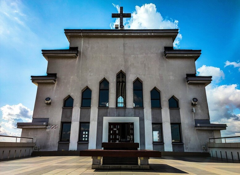 A church with a cross on top, arched windows, and a bench in front. 5