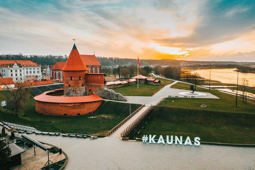 A historic tower and buildings in Kaunas, Lithuania, with a sunset in the background. 1