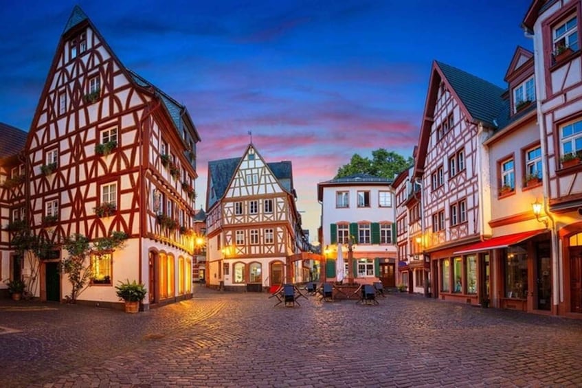A cobblestone street lined with traditional half-timbered buildings, a clear sky, and a sunset. 3