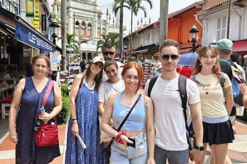 A group of people standing on a street with shops and buildings in the background. 3