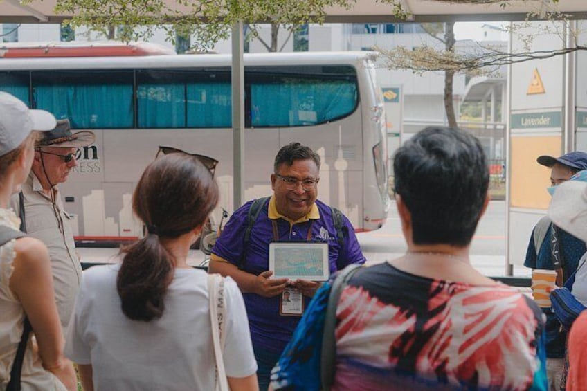 A group of people standing in front of a bus, with one person holding a tablet. 5