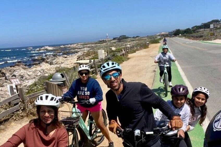 Un grupo de personas en bicicletas recorre una carretera costera con vistas al océano. 5