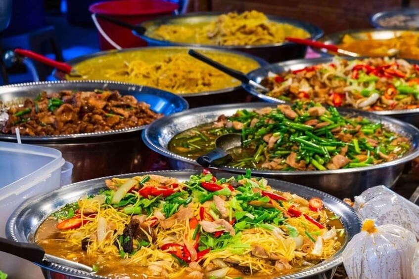 A variety of dishes in metal serving dishes, including noodles, stir-fried vegetables, and other Asian cuisine. 5
