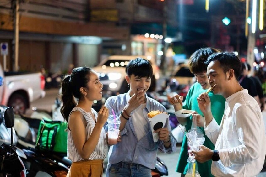 A group of people eating street food at night in an urban setting. 2