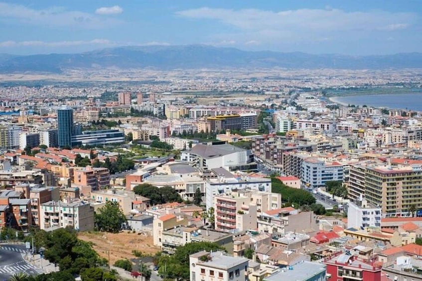 A panoramic view of a coastal city with a mix of modern and traditional architecture, a dense urban layout, and a backdrop of mountains. 2