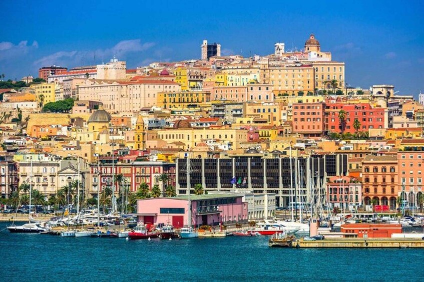 A coastal cityscape with colorful buildings, a marina with boats, and a prominent hilltop structure. 1