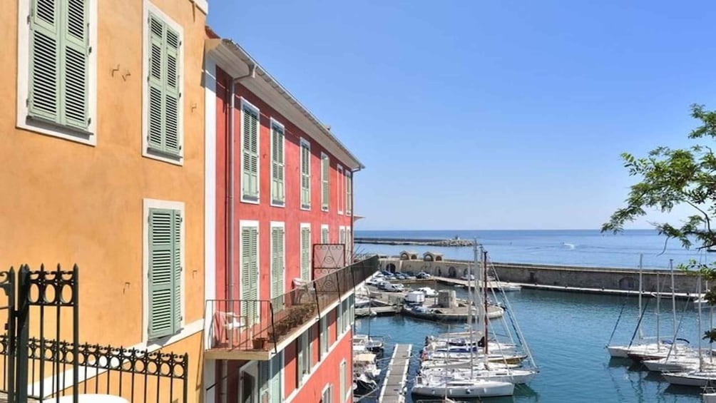 A coastal marina with boats docked, a building with green shutters, and a clear blue sky. 4