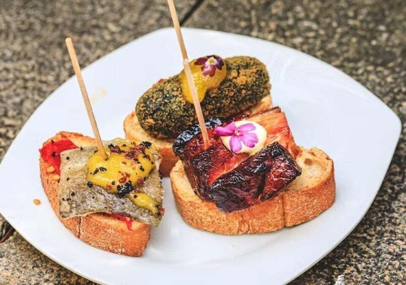 Three pieces of toast with different toppings on a white plate. 1