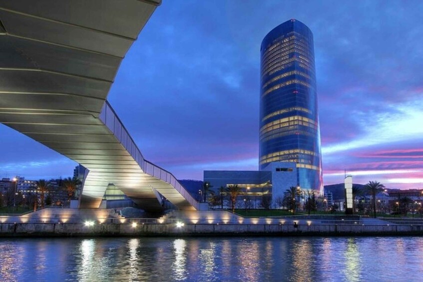 A modern bridge with a unique design, a tall skyscraper, and a calm river reflecting the city lights. 2