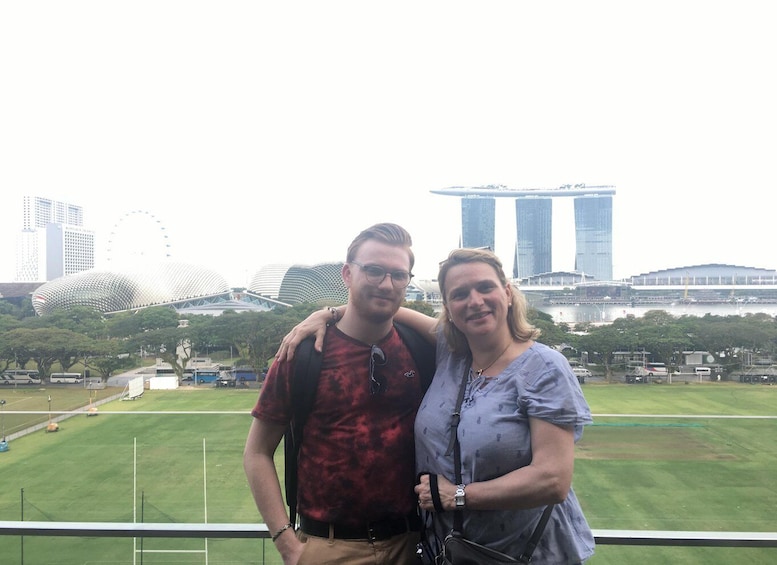 Two people standing with a cityscape in the background including a large stadium and modern buildings. 5