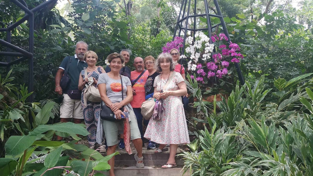 A group of people standing on a stone staircase surrounded by lush greenery and flowering plants. 1