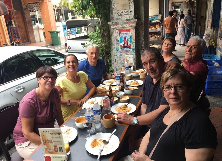 A group of people dining outdoors at a table with various dishes and drinks. 3