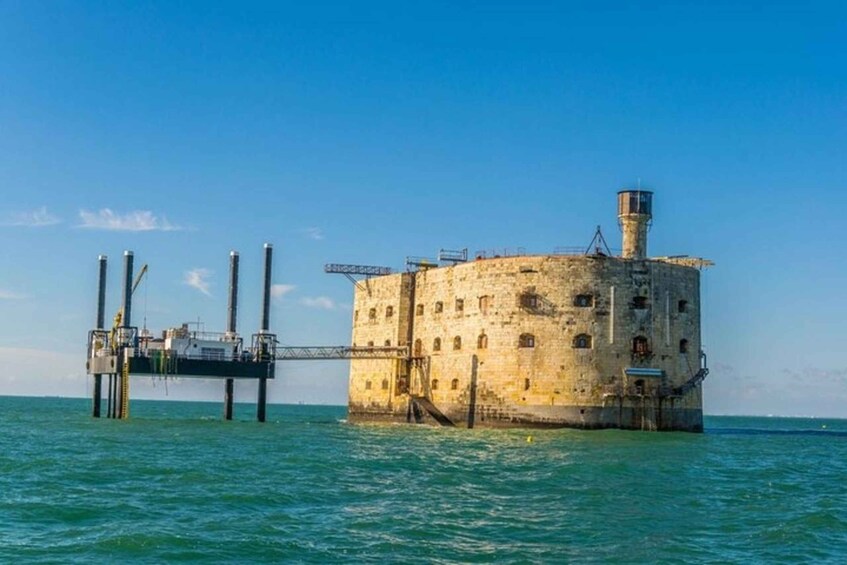 A historic stone structure with a lighthouse on a pier extending into the sea. 1