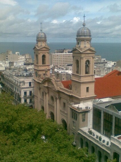 A coastal cityscape with a prominent church featuring two domed towers and a red-roofed building. 3