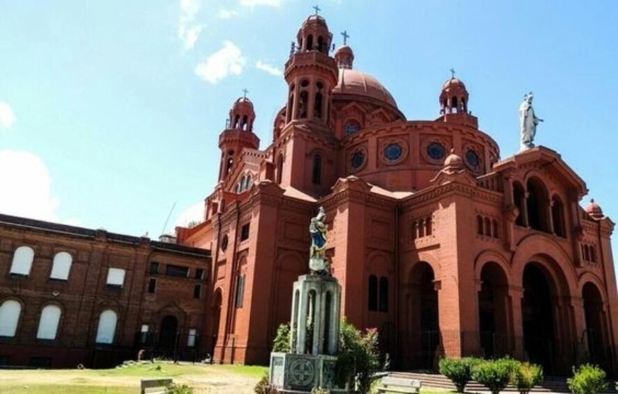 A large red-brick church with multiple domes and statues. 1