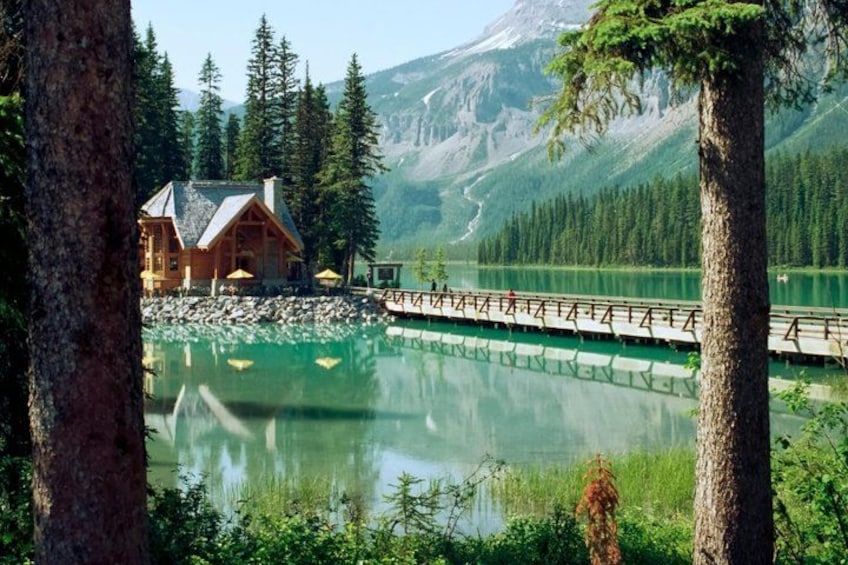 A lodge by a lake with a wooden deck extending over the water. 2
