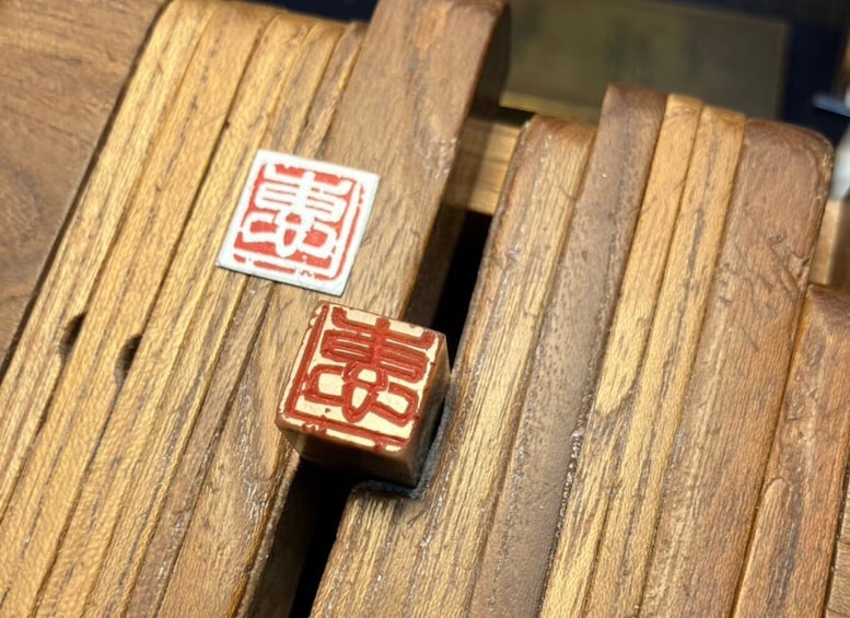 Two wooden plaques with red and white designs on a wooden surface. 4