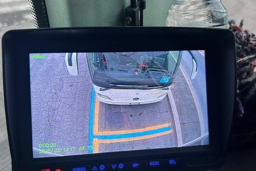 A vehicle's dashboard with a rearview camera feed, a digital clock, and a menu button. 5