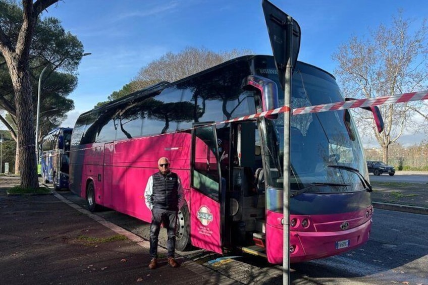 A pink bus parked on a street with a person standing next to it. 3