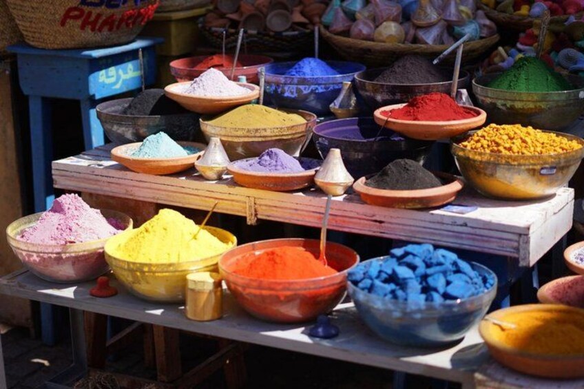 A variety of colorful powders displayed in bowls on a wooden table. 3