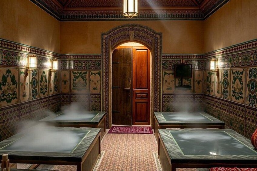A traditional hammam with ornate tile walls, a central wooden door, and steam-filled tubs. 3