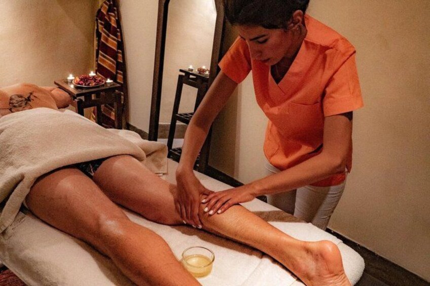 A person receiving a massage in a spa setting with candles and a towel. 4