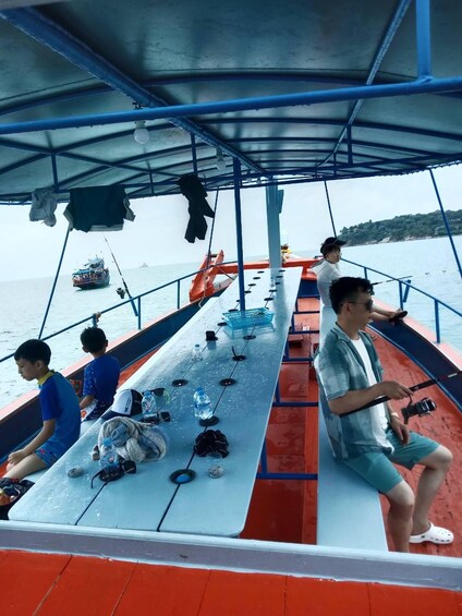 A boat with people fishing, a covered area, and a distant shoreline. 2