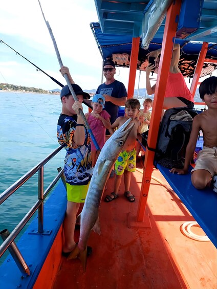 A group of people on a boat with a large fish. 3