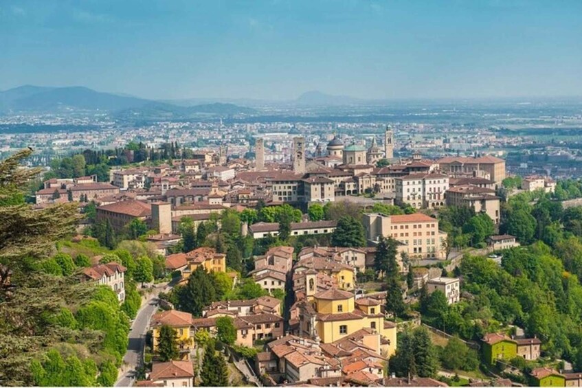 A panoramic view of a historic city with dense architecture, a prominent tower, and surrounding greenery. 2