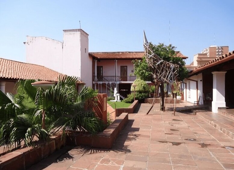 A courtyard with tiled roofs, a white building, and palm trees. 2