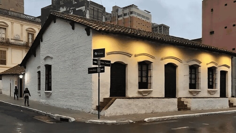 A white building with a tiled roof and a signpost. 3