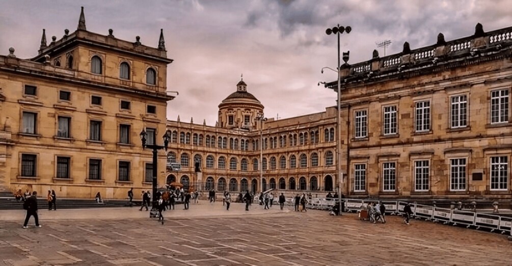 Ein historischer Platz mit klassischer Architektur, darunter ein markantes Gebäude mit einer Kuppel und Bogenfenstern. 1