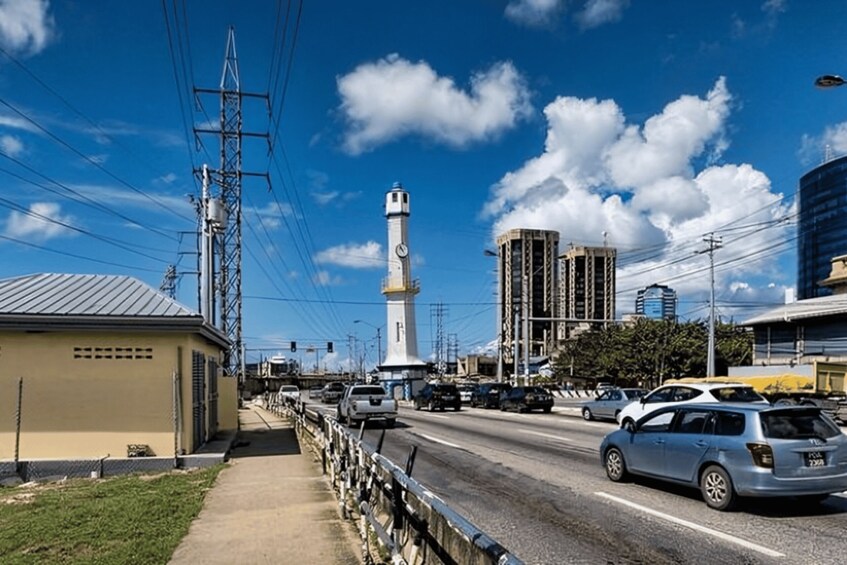 A city street with cars, a lighthouse, power lines, and buildings. 3