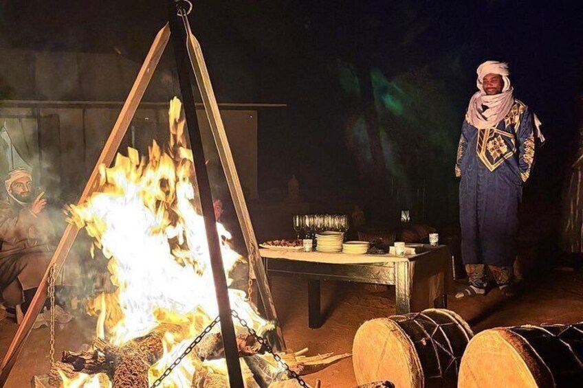 A traditional cooking setup with a large fire, cooking utensils, and a person in traditional attire. 2
