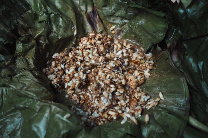 A dish with rice and possibly meat, wrapped in a green leaf. 3